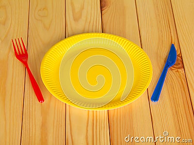 Yellow disposable plates, plastic knife and fork on light wood Stock Photo