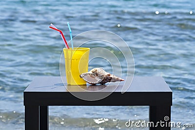 Drinking glass and seashell in fronf of blue sea Stock Photo