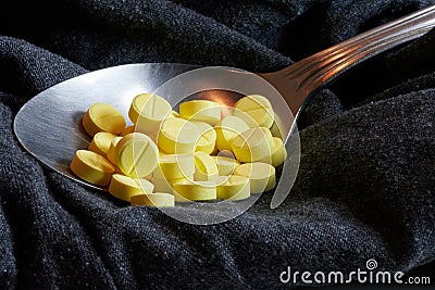 yellow drugs on spoon with black background Stock Photo