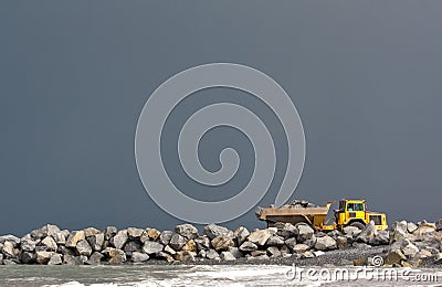 Yellow dumper truck building coastal defence works Stock Photo