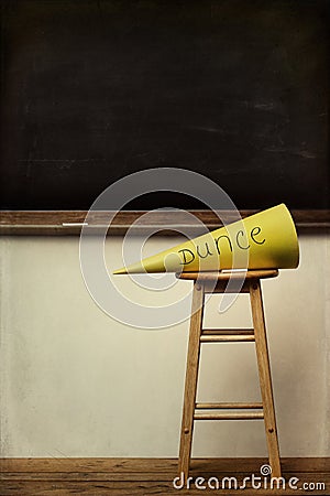Yellow dunce hat on stool with chalkboard Stock Photo