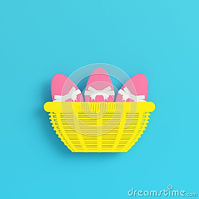 Yellow easter eggs with bow in a wicker basket on bright blue background in pastel colors Stock Photo