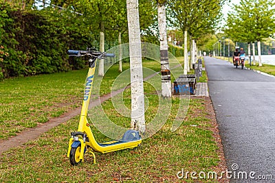 Yellow electric scooter on the lawn. Jogging path. Healthy lifestyle. Editorial Stock Photo