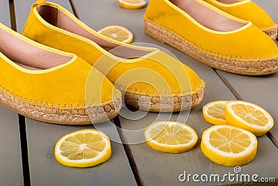 Yellow espadrilles shoes near slices of lemon on wooden background. Close up. Stock Photo