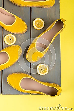 Yellow espadrilles shoes near slices of lemon on wooden background. Top view. Stock Photo