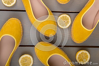 Yellow espadrilles shoes near slices of lemon on wooden background. Top view. Stock Photo