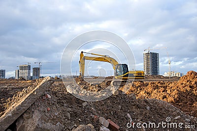 Yellow Excavator at building under construction. Backhoe digs the ground for the foundation and for laying sewer pipes. Stock Photo