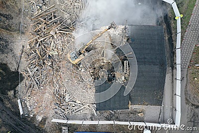 Yellow excavator destroys building. Heavy duty machine is demolishing a brick building. Demolition of the building . Demolition Editorial Stock Photo