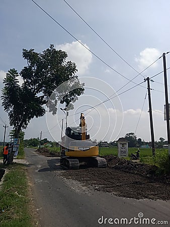 Yellow excavator in the middle of the road clearing lumps of material Editorial Stock Photo