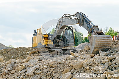 A yellow excavator on a pile of gravel Stock Photo