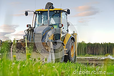 Yellow Excavator. yellow tractor on the field. Construction Machinery On Field. large yellow wheel loader aligns a piece Stock Photo