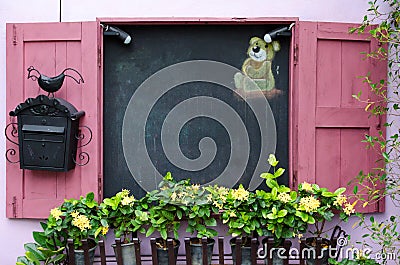 Yellow flower in plant pots growing on pink windows and blackboard Stock Photo