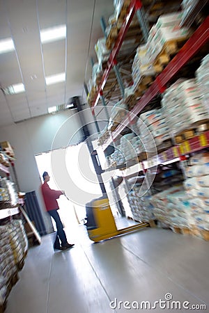 Yellow fork lifter work in big warehouse. In blur. Stock Photo