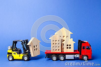 A yellow forklift loads a house figures on a red truck. Concept of transportation and cargo shipping, moving company. Construction Stock Photo