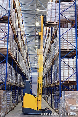 Yellow forklift raises palletising on top shelf of the rack. Editorial Stock Photo