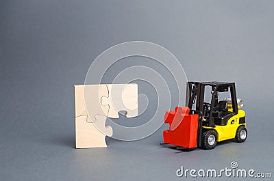 The yellow forklift truck brings the missing red puzzle to the unfinished construction. Completion of project, a key element Stock Photo