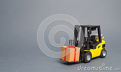 Yellow forklift truck carries a gift with a red bow. Purchase and delivery of a present. retail, discounts and contests Stock Photo