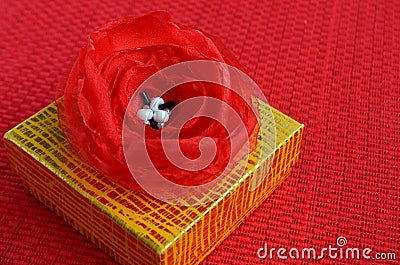 Yellow gift box with red fabric flower decoration close up Stock Photo