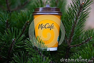 A yellow glass of McDonald's coffee on spruce paws. Editorial Stock Photo