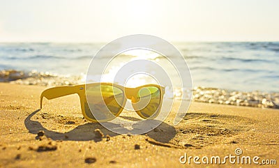Yellow glasses the sea sand, sunglasses with beautiful sea scenery. sunglasses are reflected in the Golden wet sand as Stock Photo