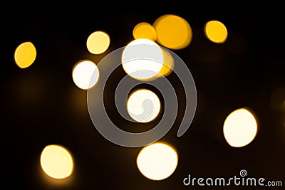 Yellow and gold lights garland in a blur on a black background. Bokeh of flying circles in the defocus. Festive atmosphere of Chri Stock Photo