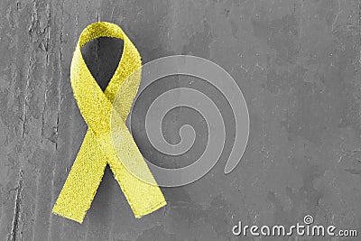 Yellow, gold ribbon on black and white wooden background, close-up, copy space, medical concept, Suicide Prevention Day Stock Photo