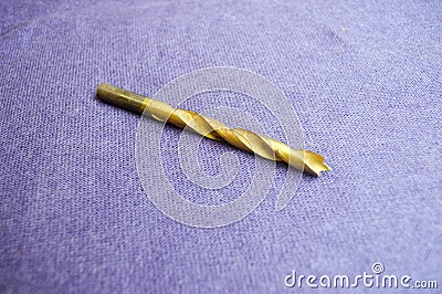 A yellow, golden drill on wood Stock Photo