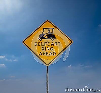 Yellow Golf Cart Crossing sign with black letters against a blue sky Stock Photo