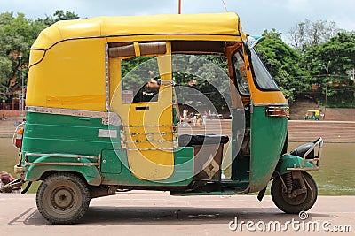 Yellow and green indian auto rickshaw. Yellow and green tuktuk near river Stock Photo