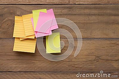 Yellow, green, pink reminder notes on a wooden board, empty space for text Stock Photo