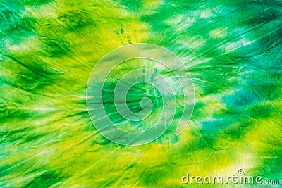 Yellow green spiral tie dye background on fabric. Flat lay. Stock Photo