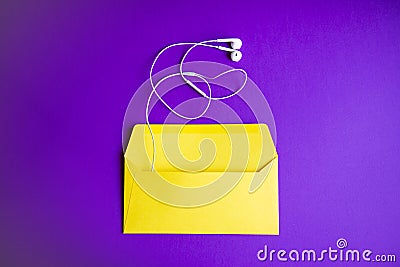 Yellow headphones on envelopment on purple background. Stock Photo