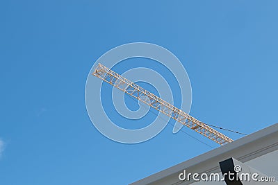 crane in yellow high long arrow at construction site with clear light blue sky day. Stock Photo