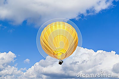 Yellow hot air balloon is suspended in the sky, with wispy white clouds in the background Stock Photo