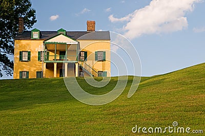 Yellow house on grassy hill Stock Photo