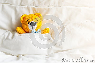Yellow ill teddy bear lying in bed on white background. Stock Photo