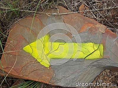 YELLOW INDICATOR ARROW ON ROCK Stock Photo