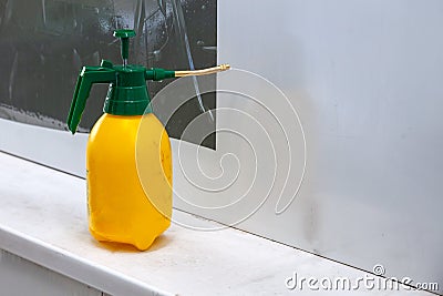 Yellow industrial sprayer with a green lid for spraying water in the workshop for pasting film on a white background. Tool for Stock Photo