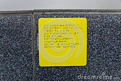 Yellow information plate with braille sign for blind on wall Stock Photo