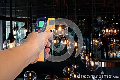 Yellow Infrared thermometer gun in hand used to measure temperature Stock Photo