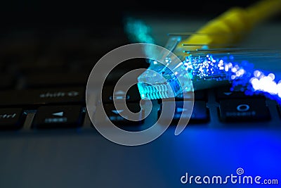 Yellow internet switch on laptop computer keyboard, glowing colorful optical fibres Stock Photo