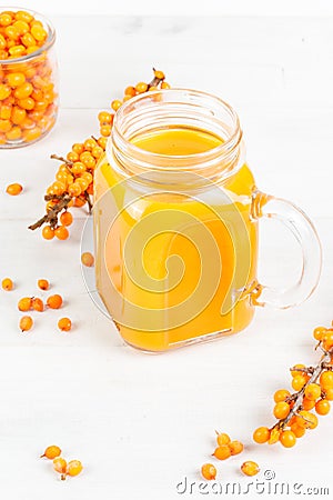 Yellow juice in a glass mug. Close-up on a white background, with sea buckthorn twigs. Stock Photo