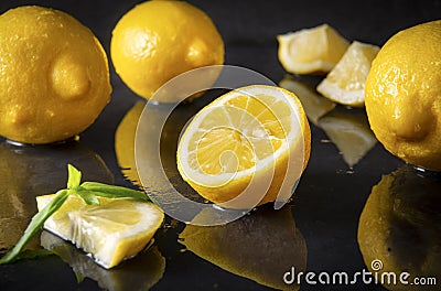 Yellow lemons with Basil on a black , half, slices and whole citrus Stock Photo