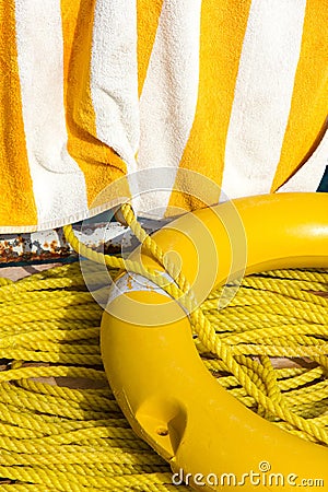 Yellow life buoy, rope and towel Stock Photo