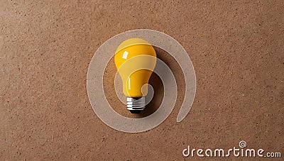 A yellow light bulb resting on a warm-toned brown surface. Stock Photo