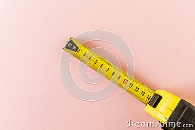 Yellow measuring tape on a pink background. Close-up Stock Photo