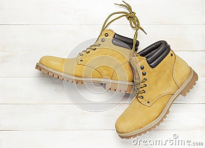 Yellow men`s work boots from natural nubuck leather on wooden white background top view flat lay with copy space. Trendy casual Stock Photo