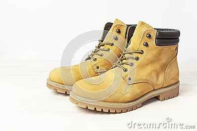 Yellow men`s work boots from natural nubuck leather on wooden white background. Trendy casual shoes, youth style. Concept of Stock Photo