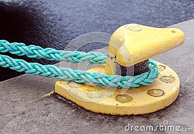 Yellow mooring bollard with green ropes Stock Photo