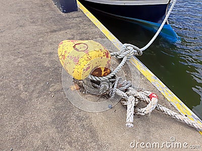 Yellow mooring bollard with ropes Stock Photo
